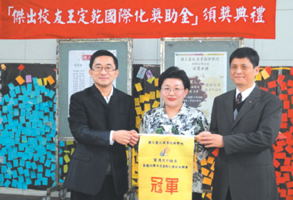 王董事長定乾及賴校長頒發團體競賽獎旗幟，由應外系陸靜容老師代表受獎
